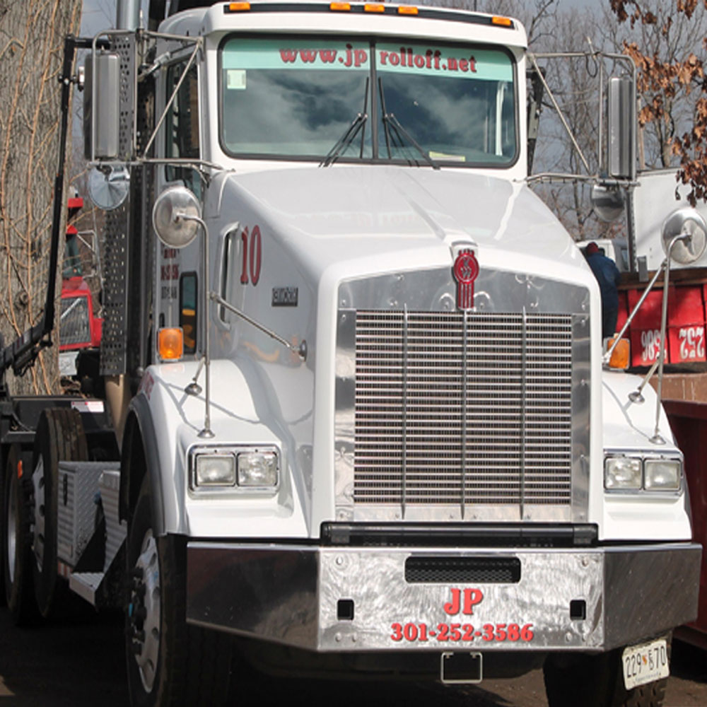 JP Roll-Off truck delivering a dumpster