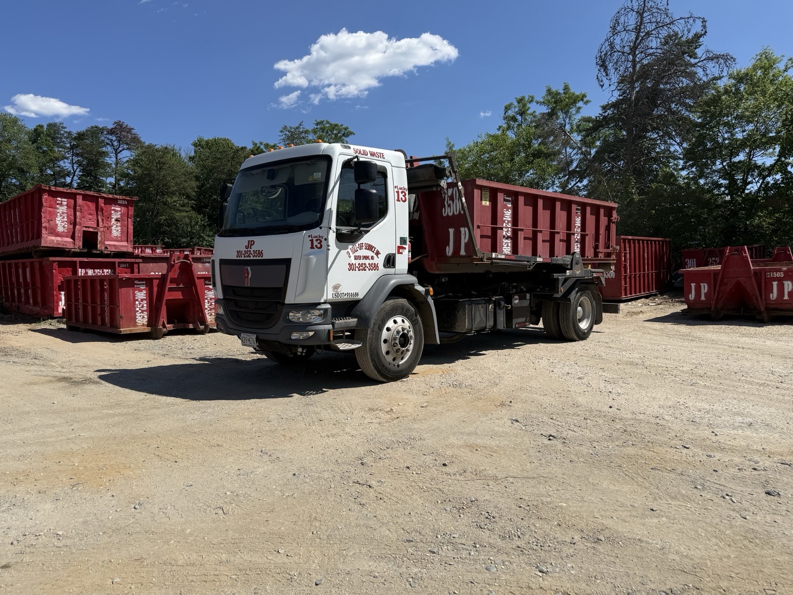 JP Roll-Off truck 13 loading a dumpster